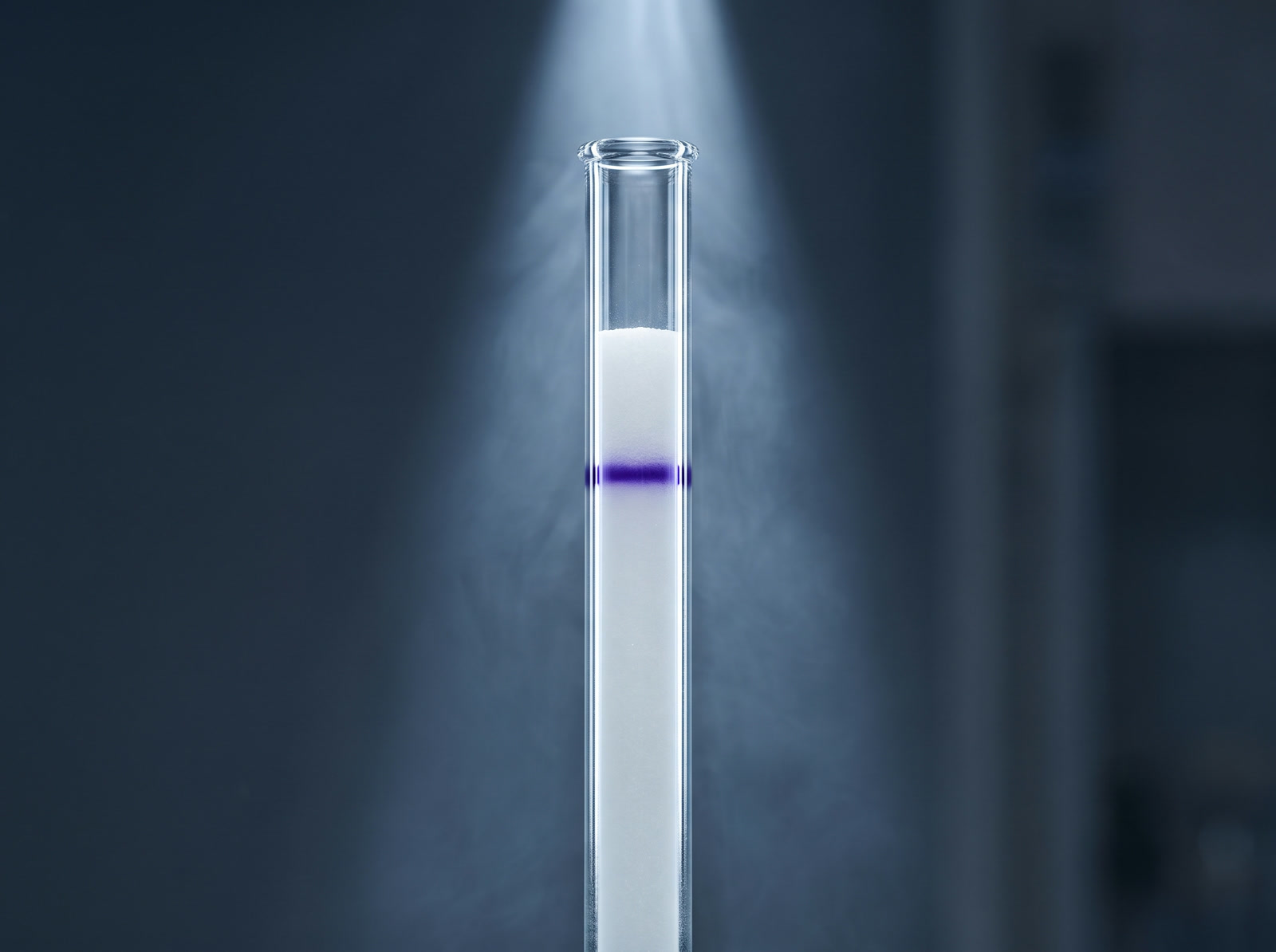 A clear glass column with a single sharp violet band in a beam of light